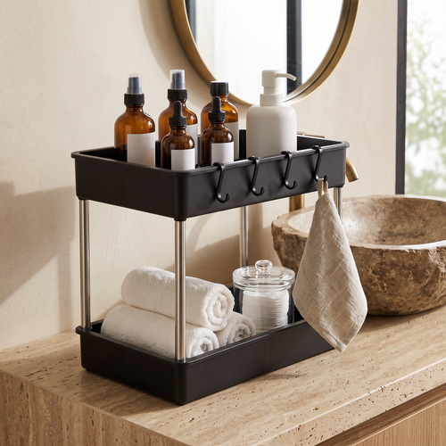 Rangement à 2 niveaux noir posé sur un meuble de salle de bain, avec flacons de soin et serviettes
